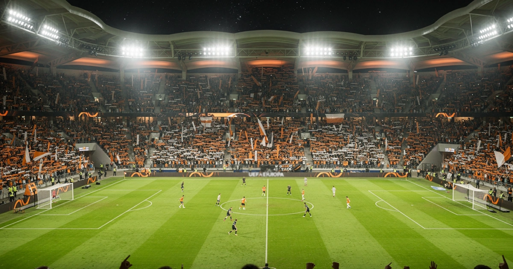Estadio de fútbol europeo iluminado durante un partido nocturno de Europa League