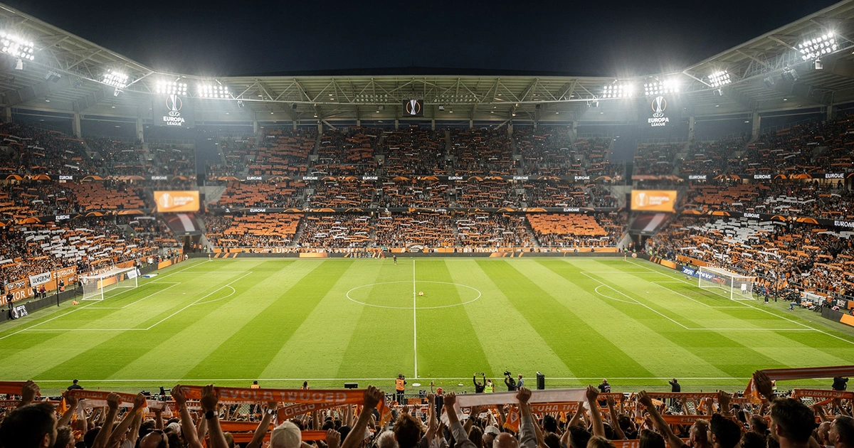 Estadio de fútbol europeo iluminado durante un partido nocturno de Europa League