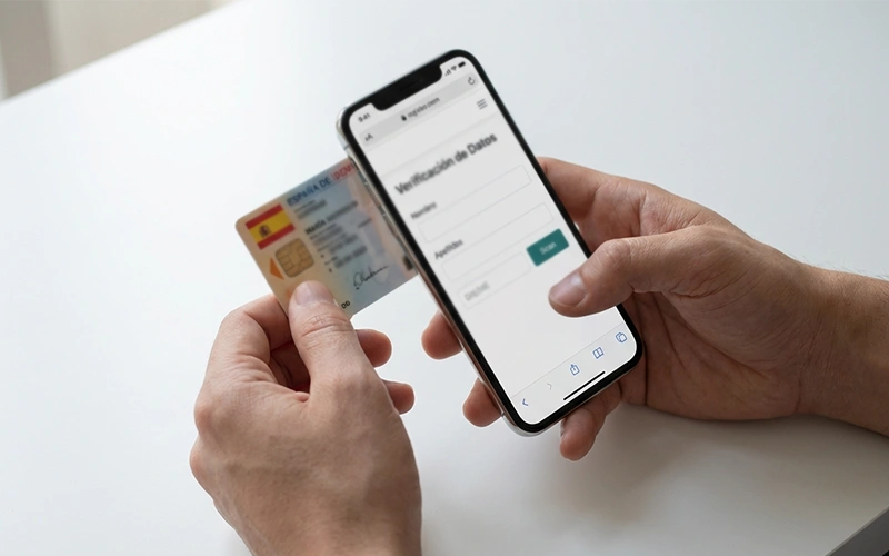 Manos sosteniendo documento de identidad junto a smartphone con formulario de registro